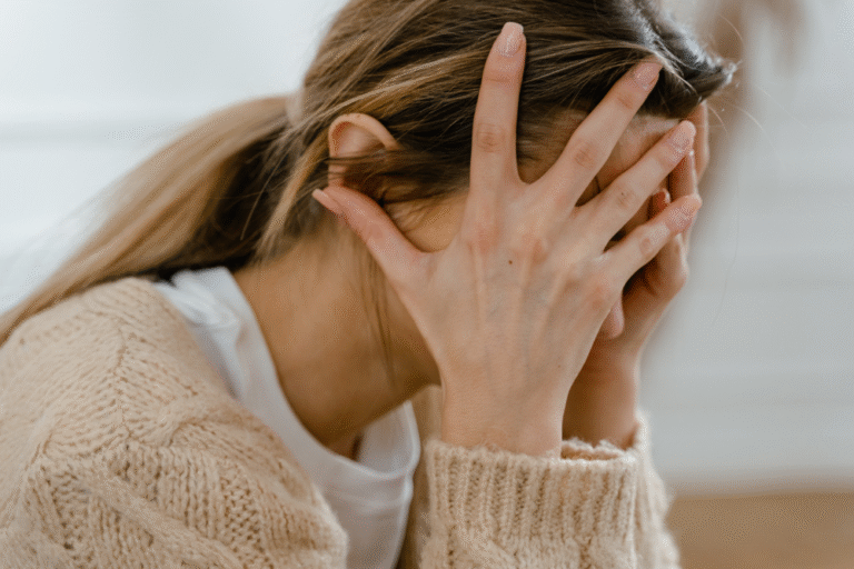 Femme stressée se tenant la tête, accompagnement par la sophrologie pour la charge mentale et l'anxiété féminine